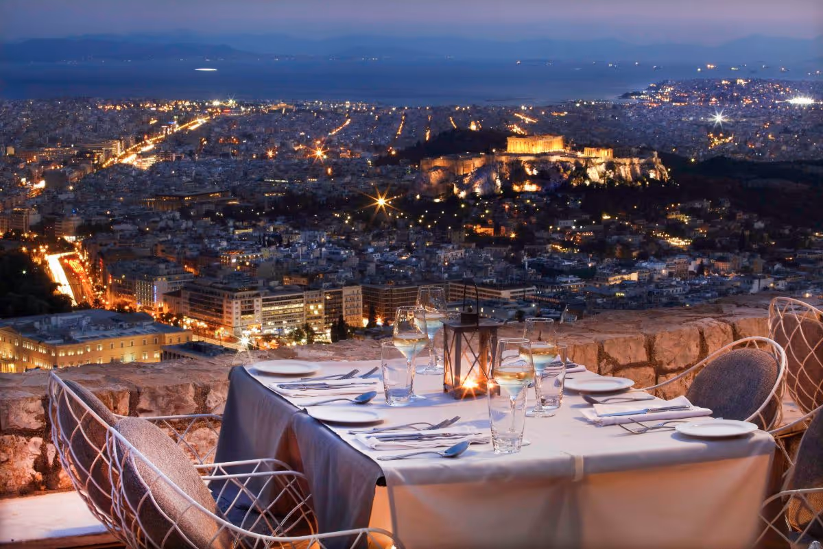 Orizontes restaurant table setting at night with panoramic views of the illuminated Acropolis and Athens city lights